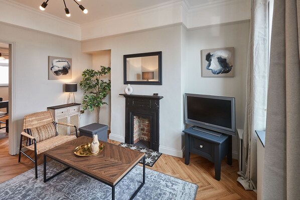A modern living room with a fireplace, a television, and artwork on the walls.
