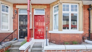 A red door with a white number plate, a black door with a white number plate, and a bay window with white trim. - Host Stay The Old Fireman s House (Saltburn-by-the-Sea)