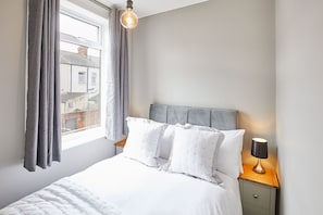 Relax in this serene bedroom with a comfortable bed, a stylish headboard, and a bedside table.