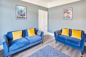 Relax in this stylish living room with two sofas, framed artworks, and a vibrant rug.