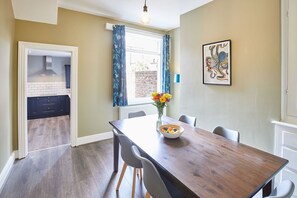 Enjoy meals in this dining area with a table for four, surrounded by a vase of flowers and a bowl of fresh fruit.