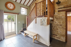 Staircase leads to an upper level, with a bench for sitting and a large clock on the wall.