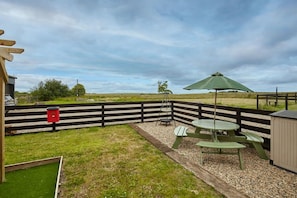 Relax in a serene patio area surrounded by a fence, featuring a picnic table and umbrella.