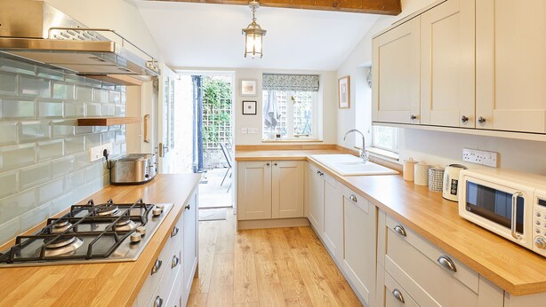 Une cuisine moderne équipée d’une cuisinière à gaz, d’un four à micro-ondes et de meubles de rangement en bois.