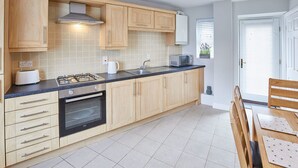 A modern kitchen with wooden cabinets, a gas stove, an oven, a microwave, and a sink. - Host Stay Aynsley Mews (Consett)