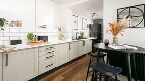 Una cocina moderna con armarios blancos, encimera negra y un comedor con mesa y sillas negras.