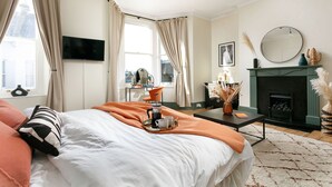 Una habitación de hotel con una cama, una mesita de café, una chimenea y un televisor en la pared.