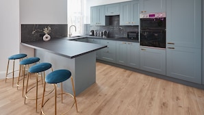 Une cuisine moderne avec des meubles gris, un îlot central doté de tabourets et des appareils électroménagers intégrés.