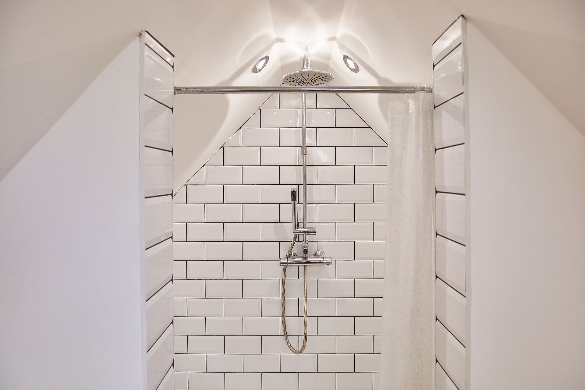Ducha con puerta de vidrio y pared de azulejos.