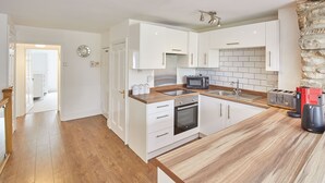A modern kitchen with white cabinets, a wooden countertop, a built-in oven, a microwave, and a toaster. - Host Stay The Duck Pond (Durham)