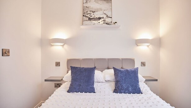 A bedroom with a bed, two nightstands, a headboard, and a wall-mounted light fixture. - Host Stay Apartment 2 Queens Court (Scarborough)