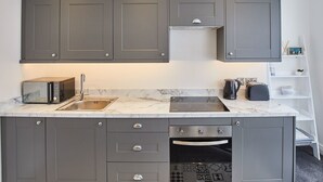 A modern kitchen with grey cabinets, a built-in microwave, a sink, a stove, and a dishwasher. - Host Stay Apartment 2 Queens Court (Scarborough)