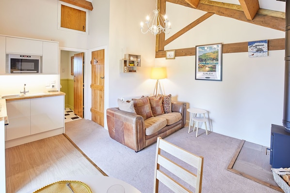 A cozy living area with a sofa, a lamp, and a framed picture on the wall. - Host Stay The Hayloft (Ilkley)