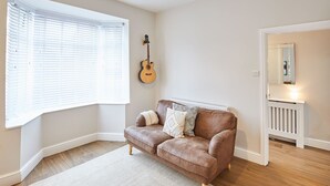 Ein Zimmer mit einem braunen Ledersofa, einem weißen Heizkörper und einer Gitarre an der Wand.