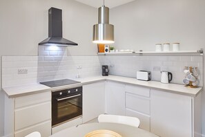 A modern kitchen with white cabinetry, a black stove, a coffee maker, and a toaster.