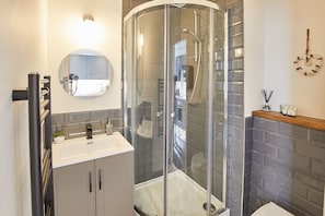 Enjoy a refreshing shower in the bathroom with a curved glass enclosure, handheld showerhead, and standalone sink.