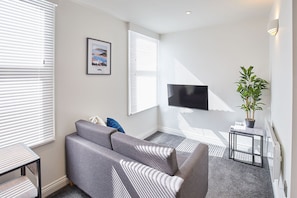 Relax in this stylish living room with a sofa, flat-screen TV, and a beautiful coastal artwork.