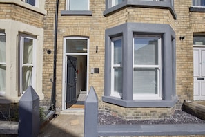 Stylish corner house with a bay window, black door, and small garden area.