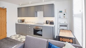 A compact kitchen with grey cabinets, a built-in oven, and a microwave.