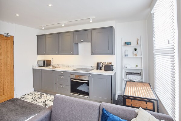 A compact kitchen with grey cabinets, a built-in oven, and a microwave.