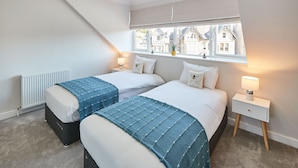 Een moderne slaapkamer met twee bedden, een raam met uitzicht op gebouwen, een radiator en bedlampjes.