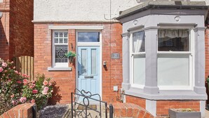 A traditional brick house with a blue door, a bay window, and a small garden with pink roses. - Host Stay Seagull Cottage (Bridlington)