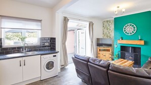 A compact living space with a kitchen, a sofa, a TV, and a fireplace. - Host Stay Seagull Cottage (Bridlington)