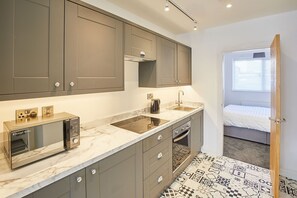 A modern kitchen with grey cabinets, a built-in microwave, and a sink. - Host Stay Apartment 1 Queens Court (Scarborough)