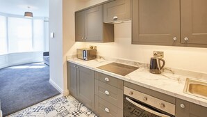 Une cuisine moderne avec des meubles gris, un plan de travail en marbre et un four encastré.