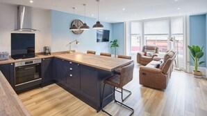 A modern kitchen with a central island, built-in oven, and pendant lighting. - Host Stay The Seaside Escape (Saltburn-by-the-Sea)