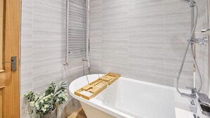 A modern bathroom with a freestanding bathtub, a showerhead, and a towel rack. - Host Stay The Seaside Escape (Saltburn-by-the-Sea)