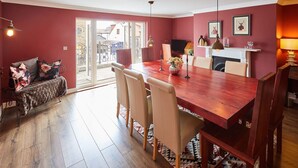 A dining area with a wooden table, beige chairs, and a red wall. - Host Stay One Mulgrave Place (Whitby)