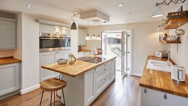 A modern kitchen with white cabinetry, a wooden island, stainless steel appliances, and pendant lighting. - Host Stay One Mulgrave Place (Whitby)