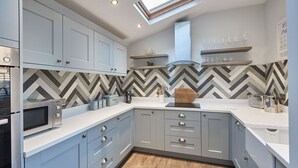 Une cuisine moderne avec des armoires grises, un dosseret en carreaux disposés en motif chevrons et une lucarne.