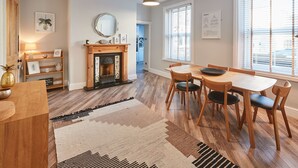 Un espace repas avec une table et des chaises en bois, une cheminée et une vue dégagée grâce à de grandes fenêtres.