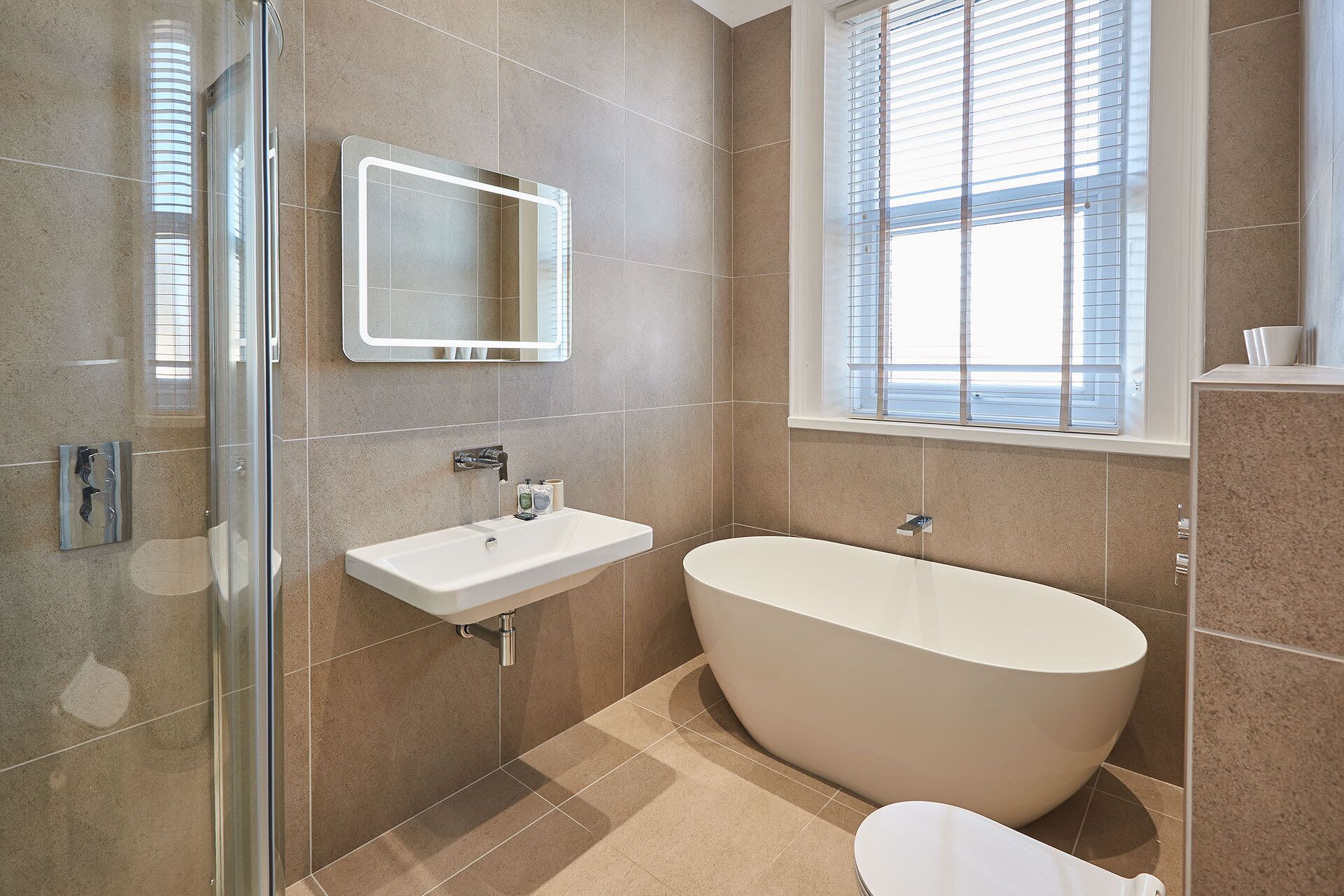 A modern bathroom with a freestanding bathtub, a glass shower enclosure, and a large mirror.