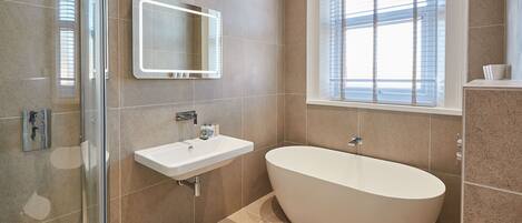 A modern bathroom with a freestanding bathtub, a glass shower enclosure, and a large mirror.