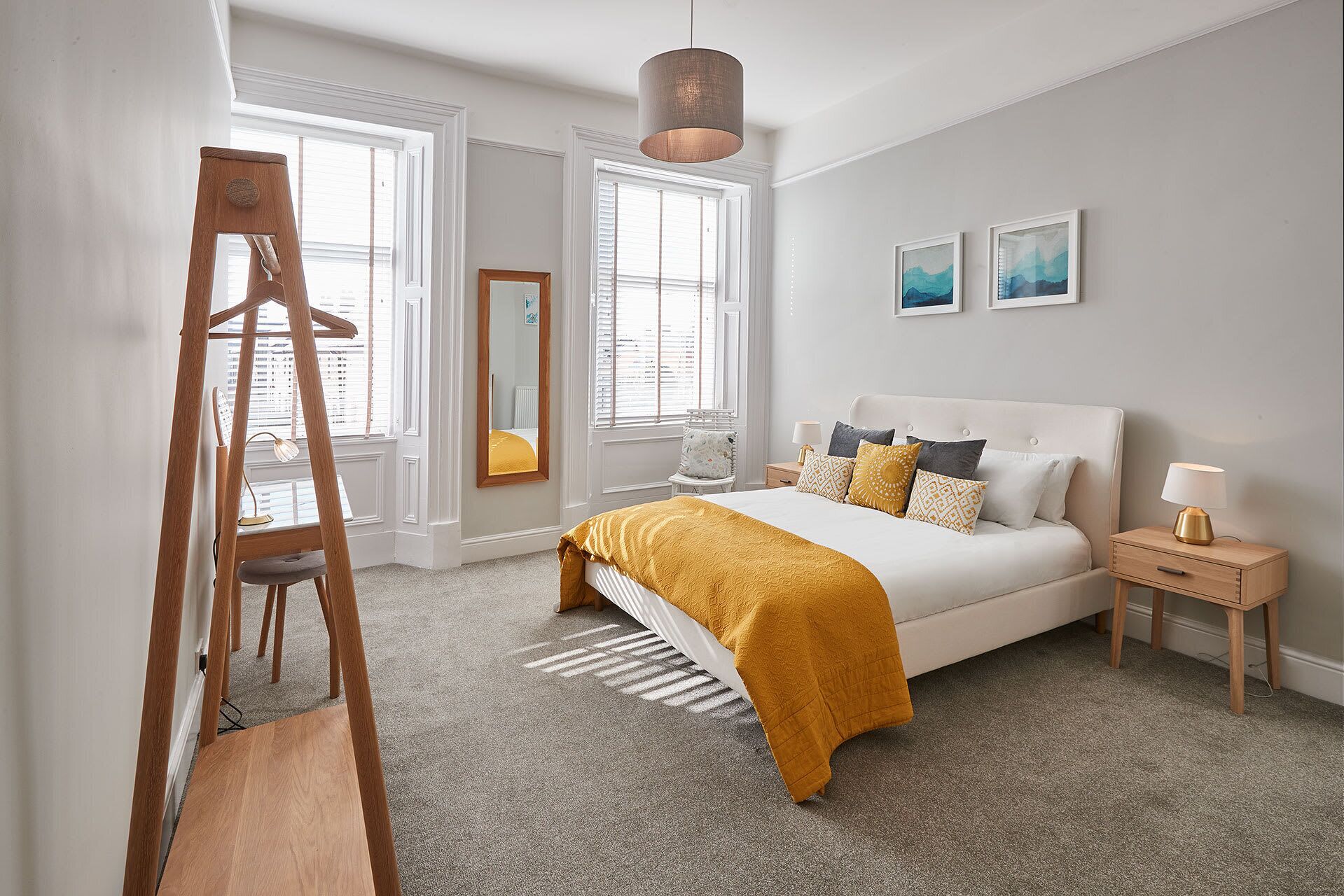 Une chambre à coucher avec un lit, des tables de chevet, une lampe, un miroir et une échelle.