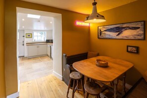 Enjoy meals in this dining area with a wooden table and stools, a unique whale painting, and a cozy bench.
