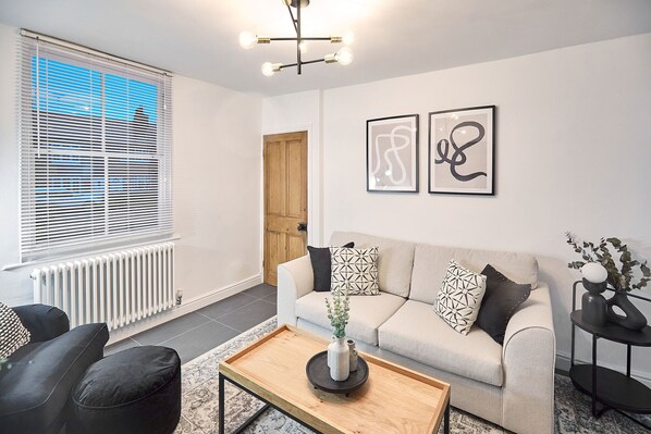 A modern living room with a sofa, coffee table, and artwork on the wall. - Host Stay High Street Cottage (Stockton-on-Tees)
