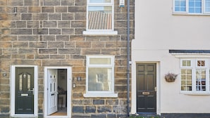 A two-story stone building with a dark green door, a white-framed window, and a number plaque indicating the address. - Host Stay Waterlily Cottage (Middlesbrough)