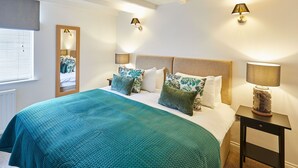 A bedroom with a bed, pillows, a nightstand, a lamp, and a mirror. - Host Stay Waterlily Cottage (Middlesbrough)
