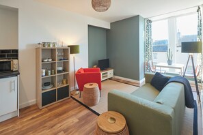 A modern living room with a sofa, a red chair, a TV, and a bookshelf.