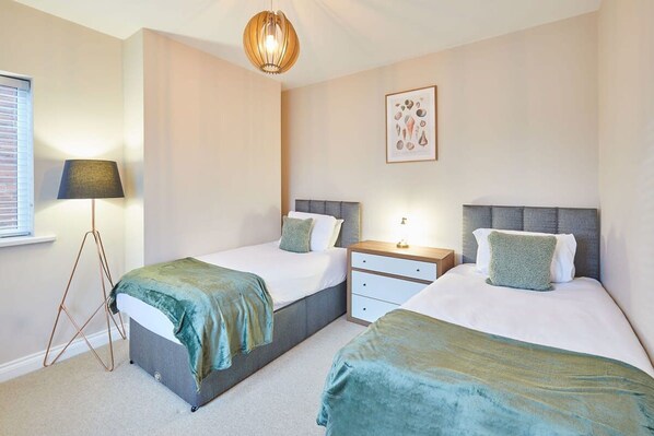 A bedroom with two beds, a bedside table, a lamp, and a framed picture on the wall. - Host Stay Watch House (Scarborough)