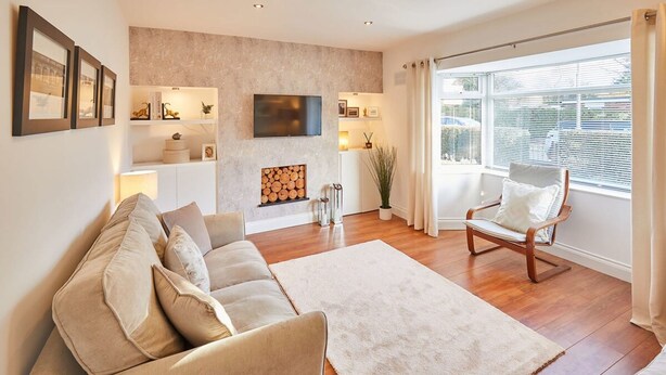 A modern living room with a sofa, armchairs, a fireplace, and a TV mounted on the wall. - Host Stay Newsam Crescent (Stockton-on-Tees)