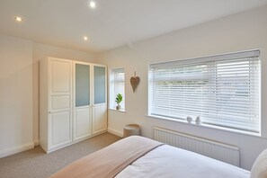 A bedroom with a bed, a wardrobe, a radiator, and a window with blinds.