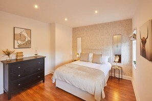 A bedroom with a bed, dresser, and artwork on the walls.