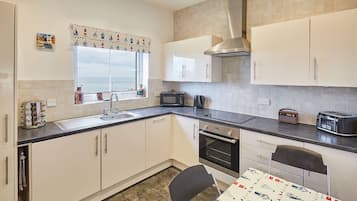 A compact kitchen with white cabinets, a microwave, a toaster, and a window with a view.