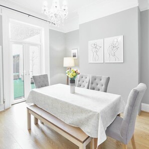 A dining area with a table set for four, a bench, and a chandelier. - Host Stay Victorian Seahouse (Saltburn-by-the-Sea)