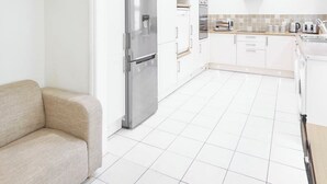 A modern kitchen with white cabinetry, a stainless steel refrigerator, and a tiled backsplash. - Host Stay Victorian Seahouse (Saltburn-by-the-Sea)